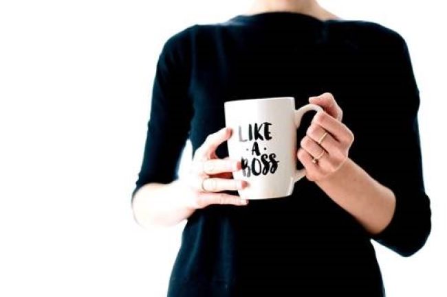 An individual holds a coffee mug with the words "like a boss" written on it.