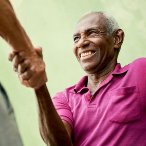 Certificate in Healthcare and Eldercare image of smiling elderly Afro-American man shaking hands with unknown person out of screen.