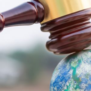 A miniature gavel raps on the top of a model of earth